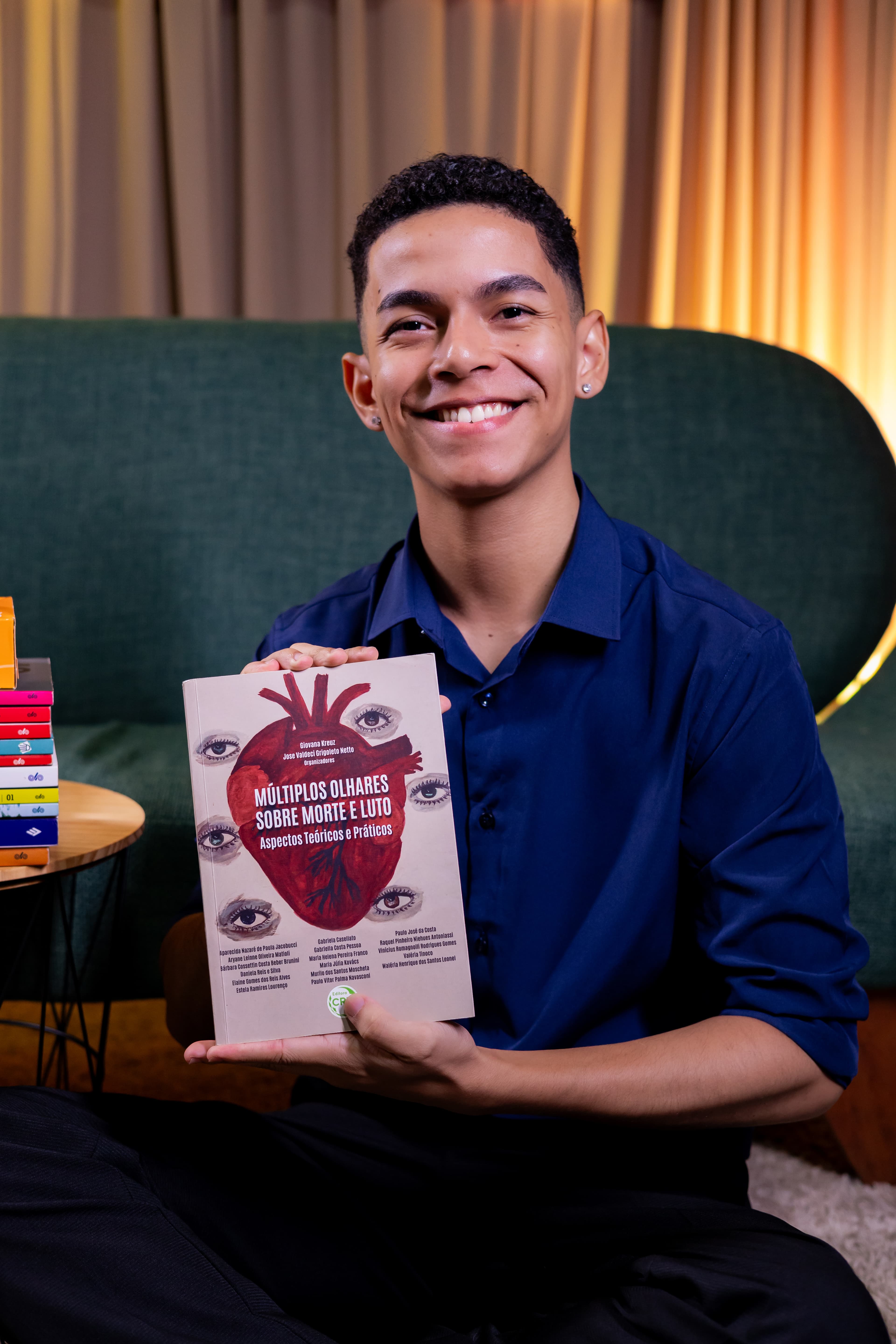 Rhamon da Silva Dias segurando um livro em um ambiente acolhedor